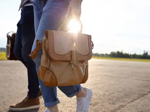 couple walking carrying travel bag runway; Courtesy begalphoto/Shutterstock