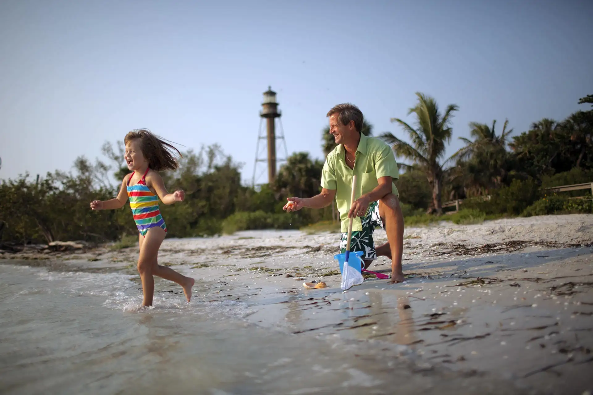 A little girl and her father playing on the beach on Sanibel Island, Florida.