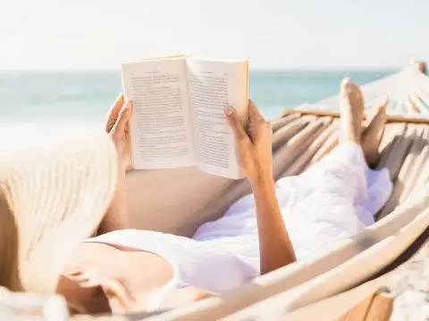 Woman Reading a Book on the Beach; Courtesy of wavebreakmedia/Shutterstock.com