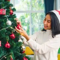 Asian women decorate Christmas tree at Christmas festival; Courtesy Tirachard Kumtanom/Shutterstock