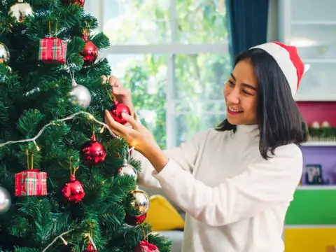 Asian women decorate Christmas tree at Christmas festival; Courtesy Tirachard Kumtanom/Shutterstock