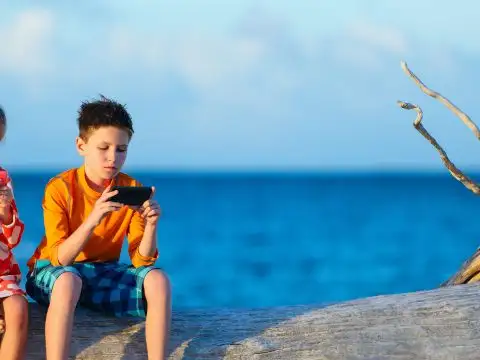 Kids on Smartphones on Beach; Courtesy of BlueOrange Studio/Shutterstock.com