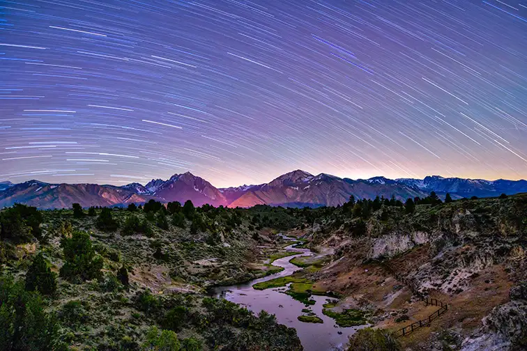 Star Trails over Hot Creek geothermal area at night with the Eastern Sierra mountains in the background, Mammoth Lakes, California; Courtesy of Bill45/Shutterstock