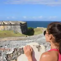 Puerto Rico travel tourist woman in San Juan, looking down at the fort Castillo San Felipe Del Morro; Courtesy of Maridav/Shutterstock