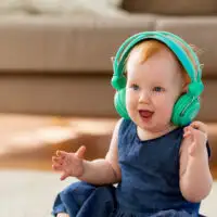 lovely redhead baby girl in headphones listening to music at home; Courtesy of Syda Productions/Shutterstock