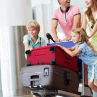Family wheeling large suitcases in airport; Courtesy of AboutLife/Shutterstock