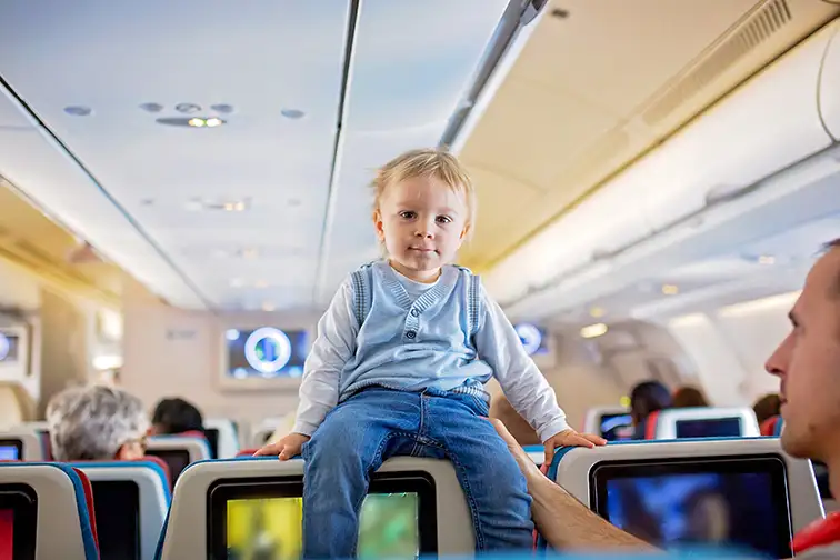 Father, entertaining little toddler boy on board of aircraft; Courtesy of Tomsickova Tatyana/Shutterstock