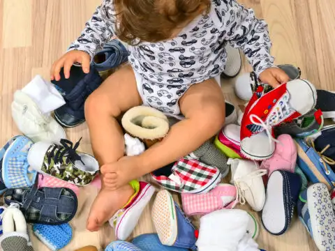 Toddler playing with a lot of baby shoes. ; Courtesy of Iulian Valentin/Shutterstock