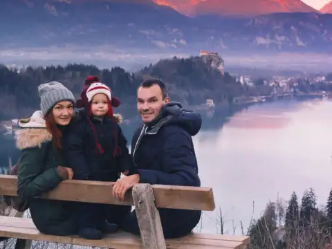 family posing for photo on lake bled in slovenia wearing weinter gear; Courtesy of Natalia Deriabina/Shutterstock