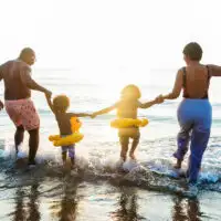 family on vacation frolicking in ocean; Courtesy of Shutterstock