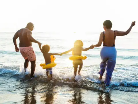 family on vacation frolicking in ocean; Courtesy of Shutterstock