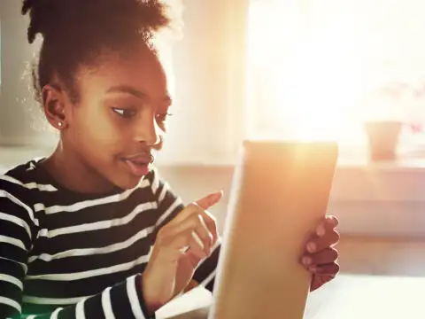 Young African-American Girl Surfing the Internet Using Tablet computer at the Table Inside Home.; Courtesy of Flamingo Images/Shutterstock