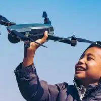 boy holding up a drone in field; Courtesy GNT STUDIO/Shutterstock