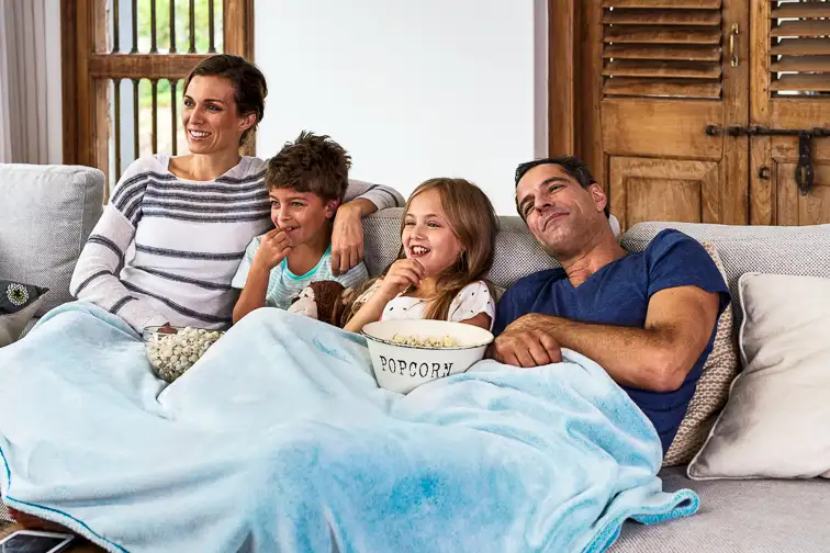 Happy family relaxing on sofa under a blanket; Courtesy Daxiao Productions/Shutterstock
