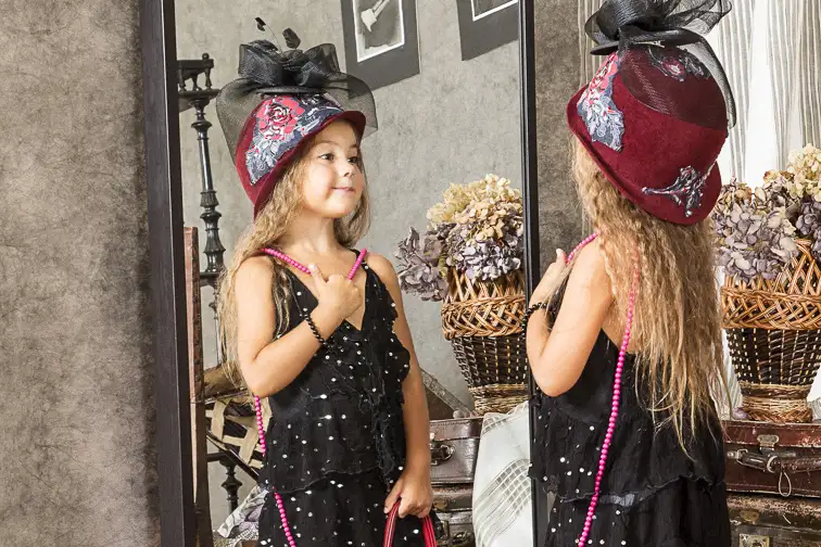 little girl playing dress-up looking in mirror; Courtesy Kuznetsov Alexey/Shutterstock