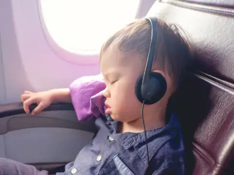 Asian Toddler Wearing Headphones on Plane; Courtesy of Yaoinlove/Shutterstock.com