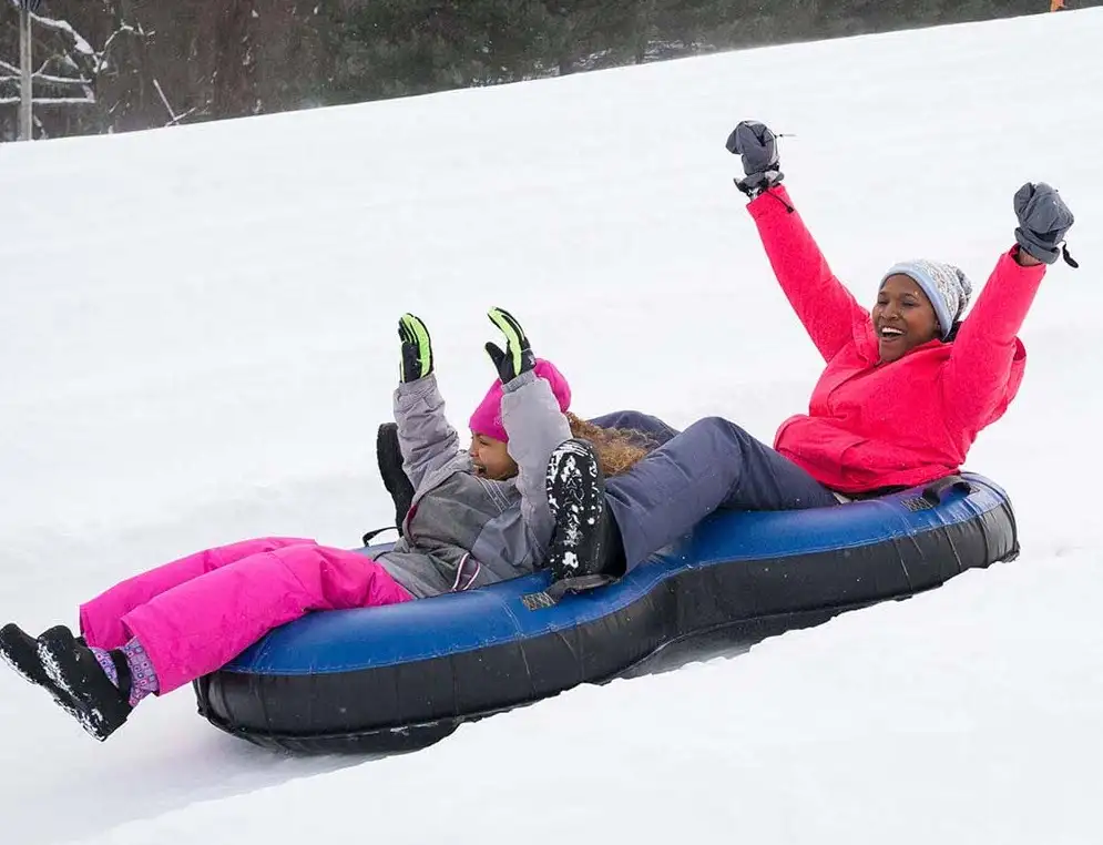 Woman and child snowtubing down a mountain