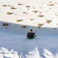 Man sliding down sand dune on sand sled