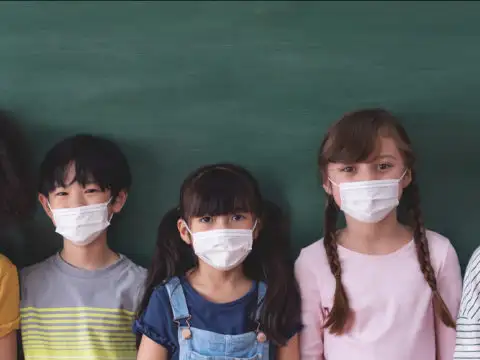 Children in front of a school chalkboard wearing protective face masks