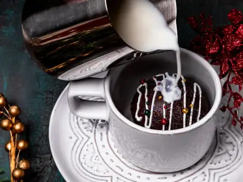 Close up of milk pouring over a hot chocolate bomb in a mug
